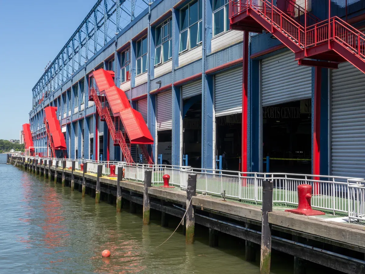 The blue-and-red Chelsea Piers sports complex building and its pier edge on the Hudson River, part of a New York architecture boat tour