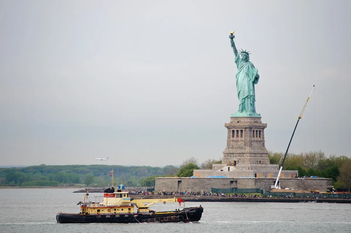 Statue of Liberty from the water with a tug passing, the view on a New York architecture boat tour