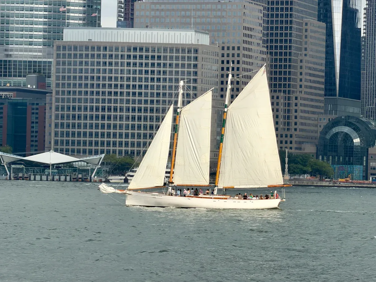 The schooner Adirondack under sail in New York Harbor with Lower Manhattan office towers behind, part of a New York architecture boat tour
